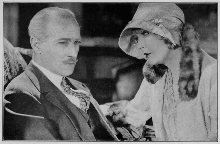 Woman in hat gazes at man in jacket and tie.