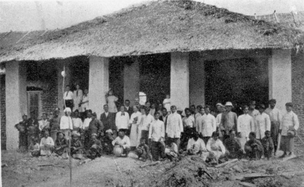 One story building with crowd posing for picture