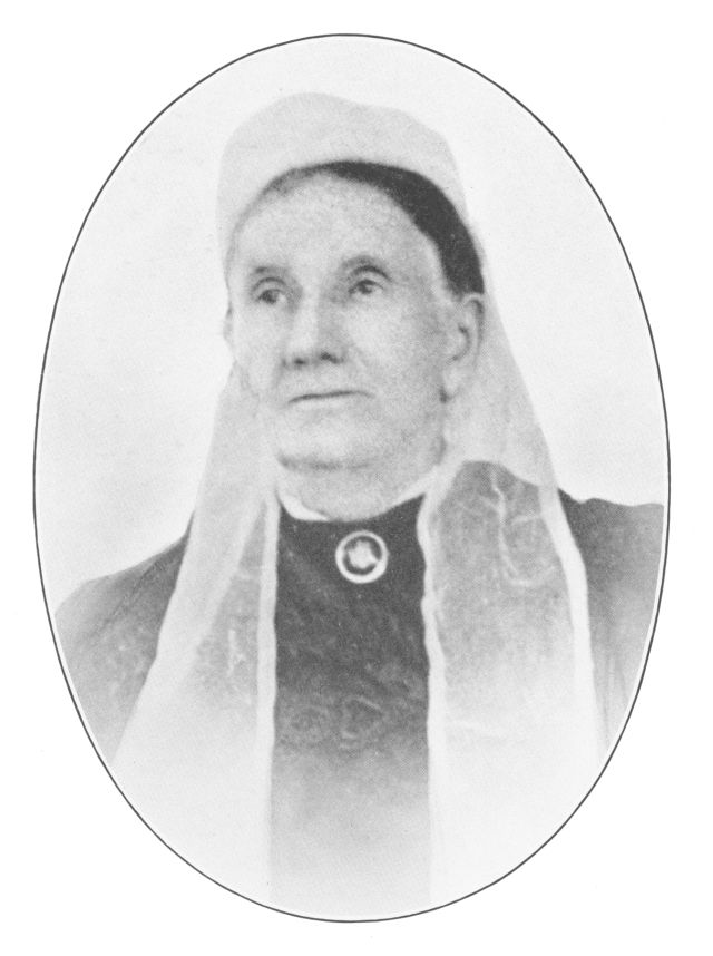 woman wearing a lace cap on her head and a brooch on at her neck