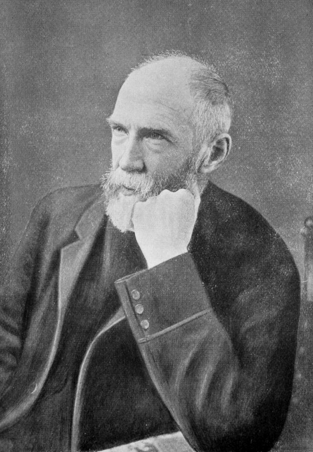 gray haired man resting his bearded chin on his fist